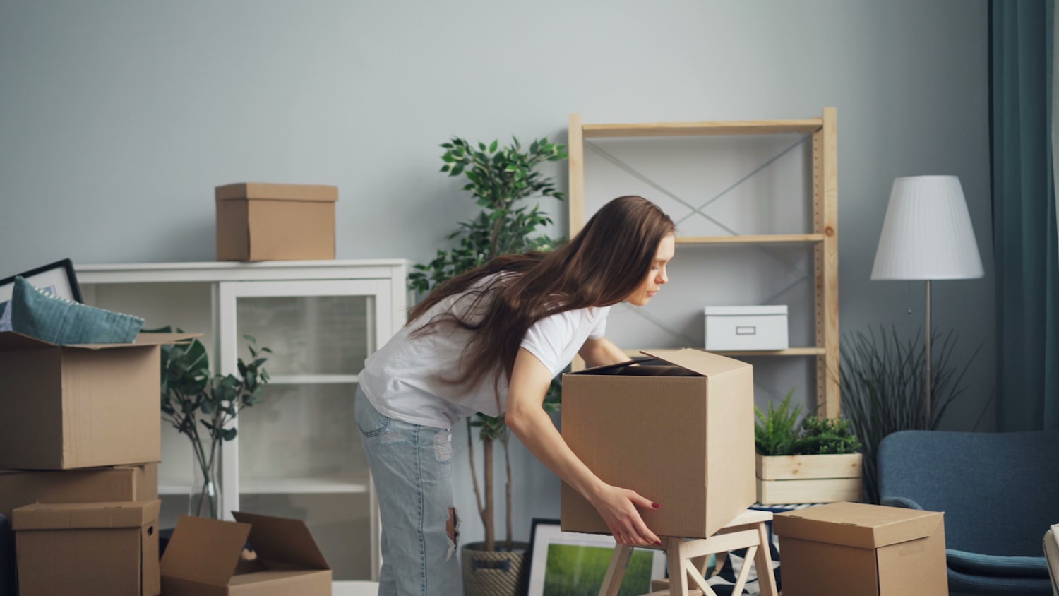 A mover carefully lifting a wrapped box in a home